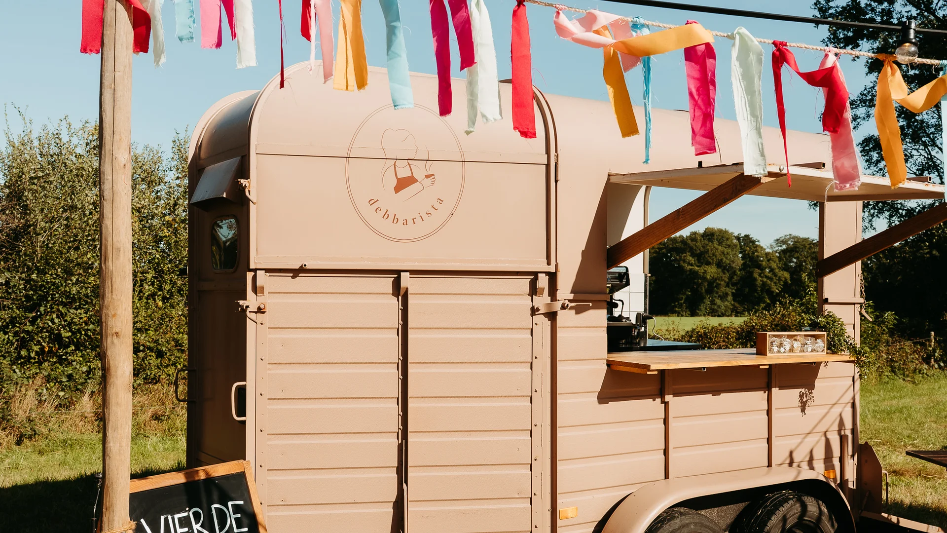Debbarista vintage koffietrailer buiten opgesteld met zomerse slingers en decoratie