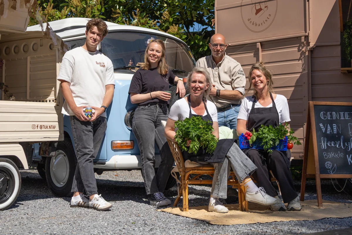 Gasten in gesprek bij de foodtrucks tijdens een zomers buitenevenement